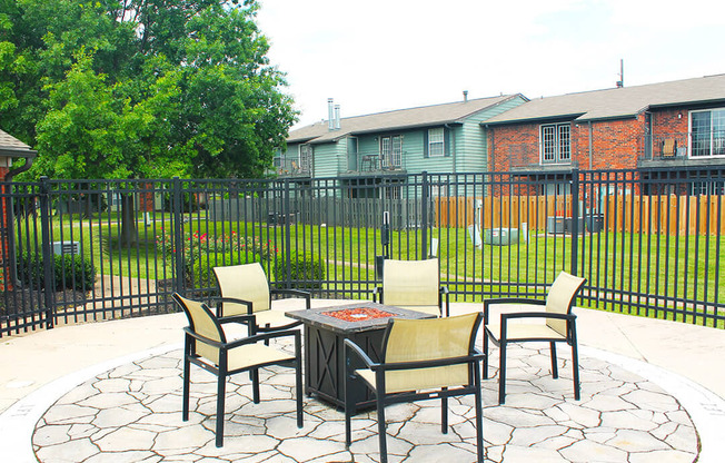 a patio with a table and chairs in front of a fence