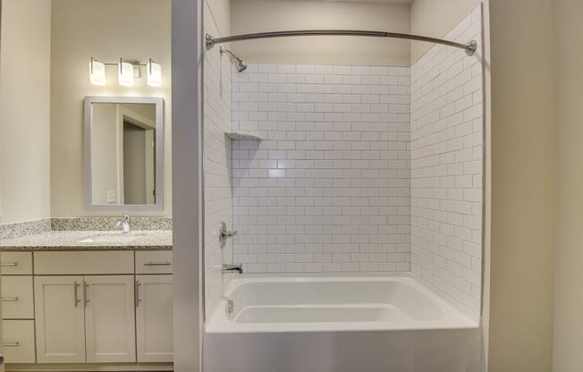 a bathroom with a tub and a sink and a mirror at The Augustan, Augusta, GA