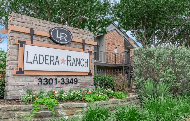 Sign for Ladera Ranch displaying the name and address (3301-3349) surrounded by lush green plants and shrubs. The structure has a stone base with a modern design, highlighting the community's welcoming environment.