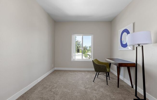 a living room with a desk and chair and a window