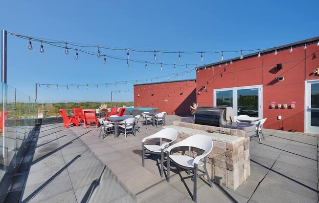 A patio with red chairs and tables is set up on a rooftop.