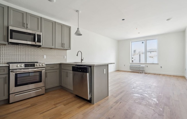an empty kitchen with stainless steel appliances and a wooden floor