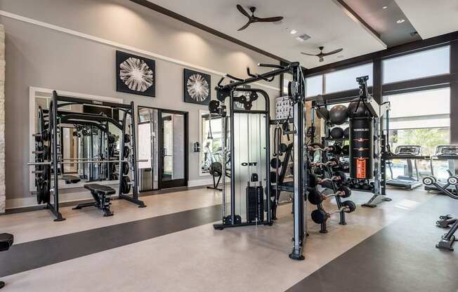 A spacious gym with a variety of equipment and a ceiling fan.