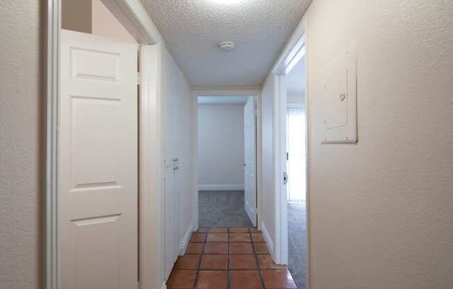 Bedroom hallway with Saltillo tile flooring and closet space at the Atrium Apartments in San Diego, California.