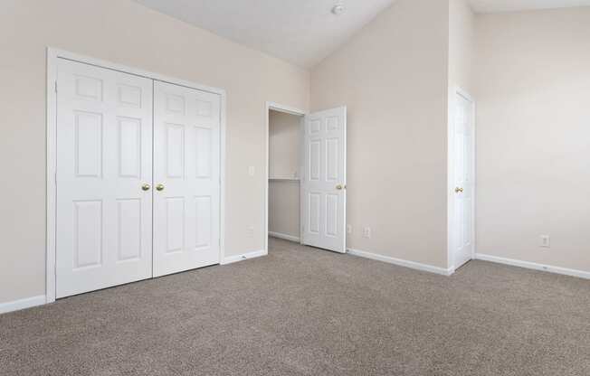 an empty bedroom with two closets and two doors