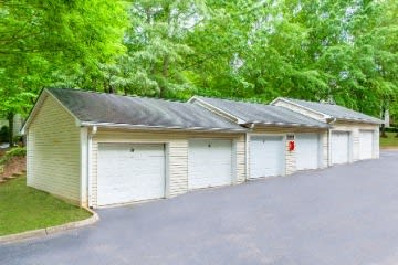 a row of white garage doors in front of trees