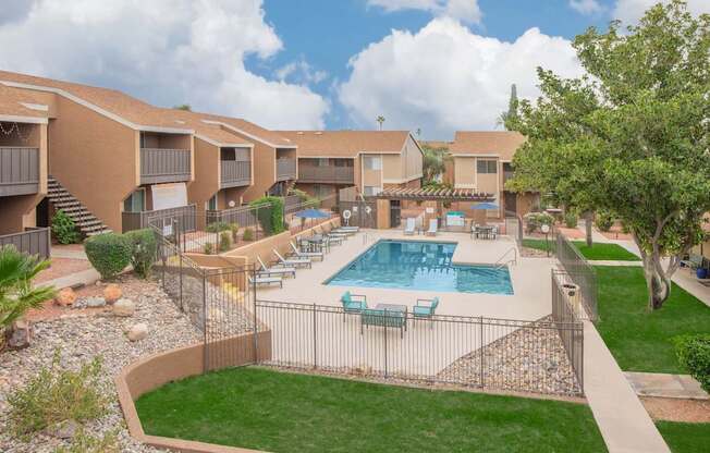 A swimming pool surrounded by a fence and chairs.
