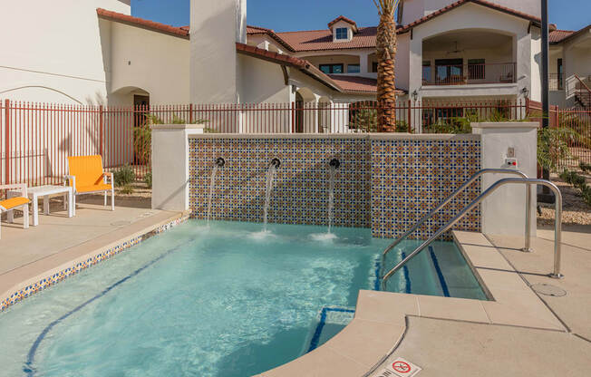 A pool with a tiled wall and a metal railing.