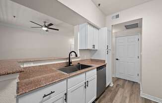A kitchen with white cabinets and a granite countertop.