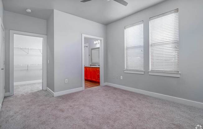 A room with a carpeted floor, a ceiling fan, and a red accent wall.