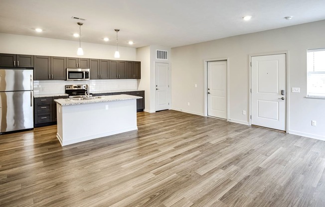 an open kitchen and living room with wood flooring