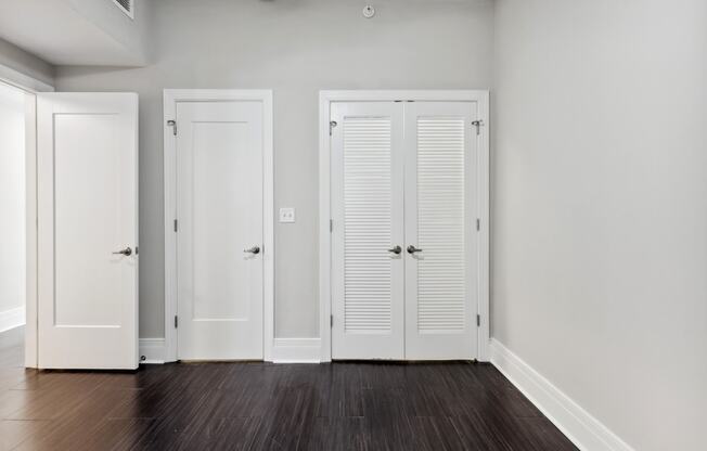 a bedroom with three doors and a hardwood floor