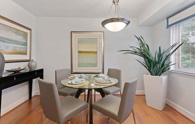 A dining room with a table set for two and a potted plant.