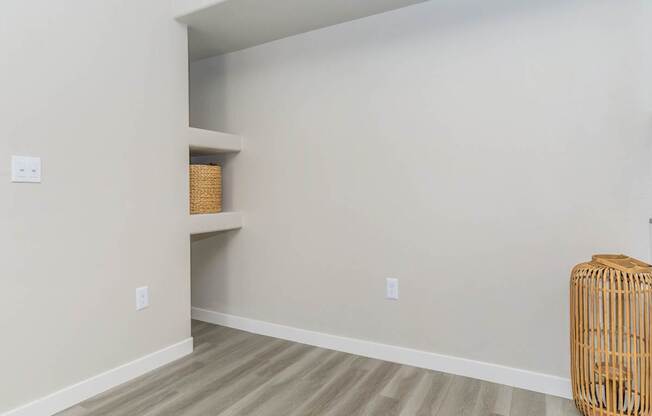A room with a tan wall and a wicker basket on the floor.