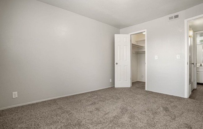 a bedroom with a carpeted floor and a door to a closet