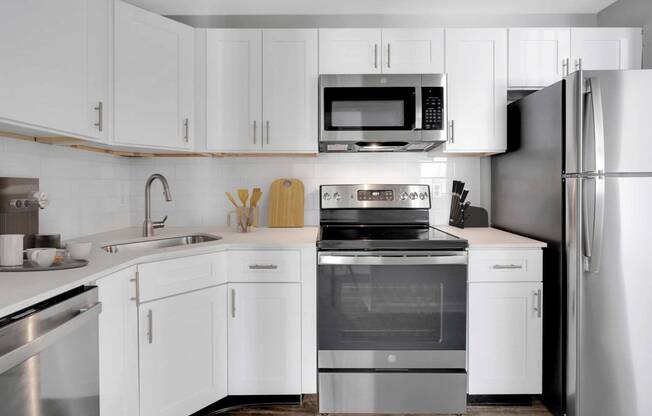 a white kitchen with stainless steel appliances and white cabinets at Station JTown, Louisville, Kentucky