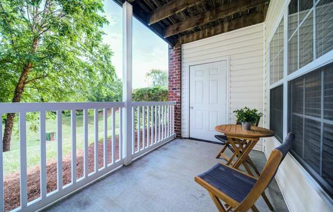 Covered Patio with 2 chairs and a table and a view of trees