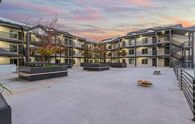 an empty courtyard with apartment buildings with a colorful sky above it