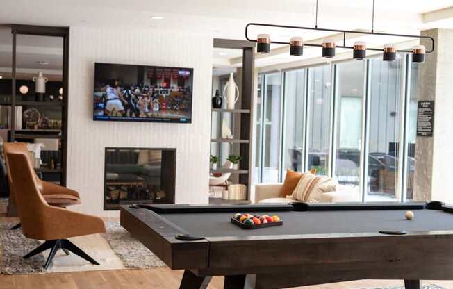 A pool table with a television in the background.