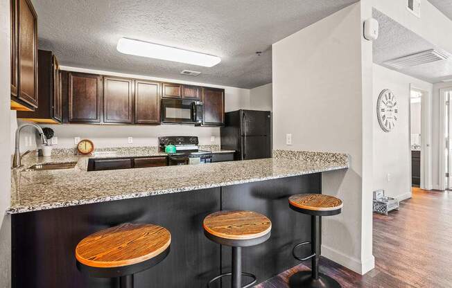A kitchen with a bar stool in front of the counter.