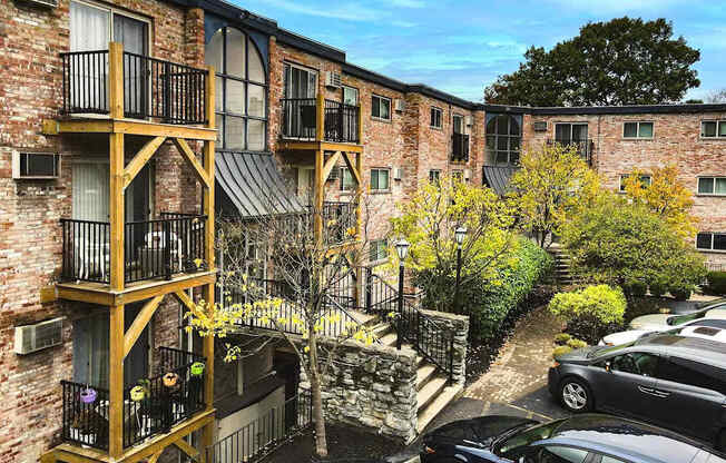 A brick building with a balcony and a tree in front.