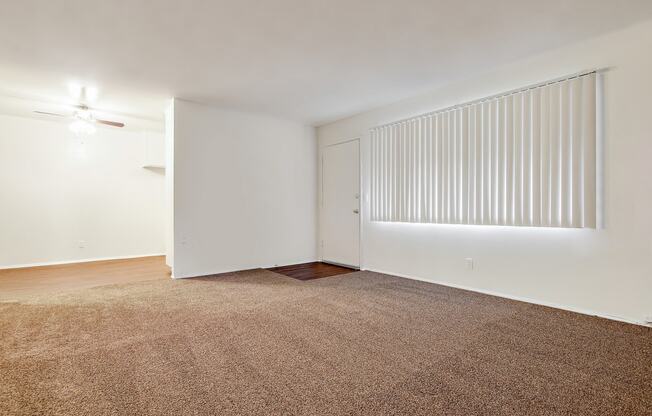 Living room with carpeted floors, wood style floors in dining area with ceiling fan