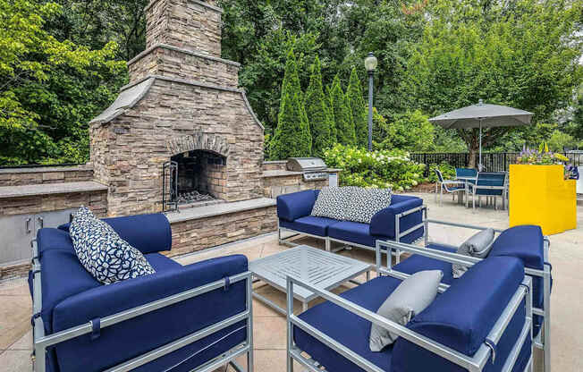 A patio with blue couches and a stone fireplace.