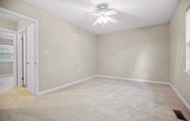 an empty room with a ceiling fan and a door to a closet