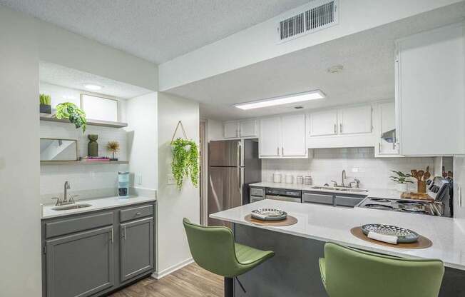 A kitchen with a white countertop and green chairs.