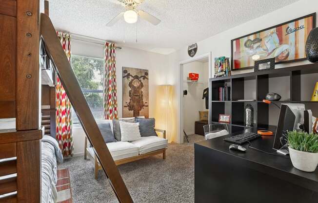 A living room with a couch, a chair, a desk, and a bookshelf.
