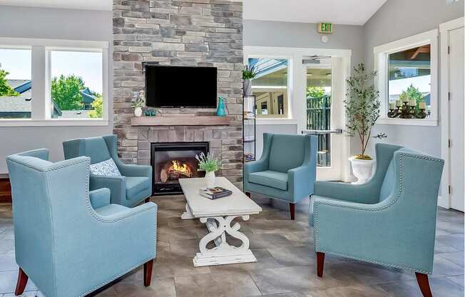 A clubhouse with a stone fireplace and a flat screen TV mounted above it at The Landing Apartments and Townhomes, Oregon, 97045