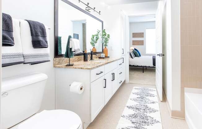 a white bathroom with a large mirror and a white toilet