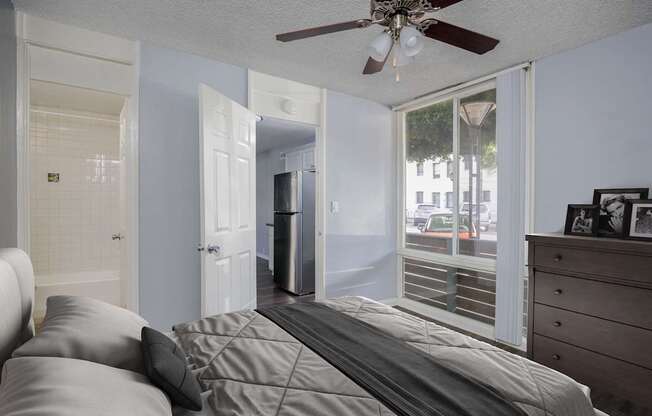 A bedroom with a bed, dresser, and a ceiling fan.