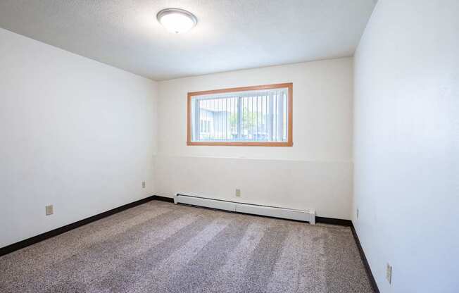 A room with a window and a carpeted floor. Fargo, ND Islander Apartments