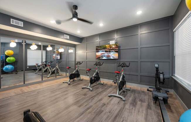 A gym with exercise equipment and a fan on the ceiling.