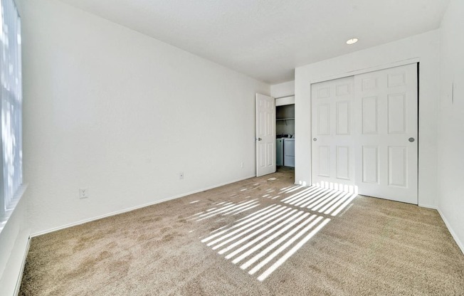 an empty living room with carpet and a door to a kitchen