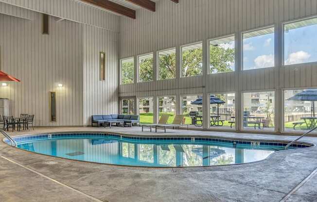 A large indoor swimming pool with a glass wall next to it.
