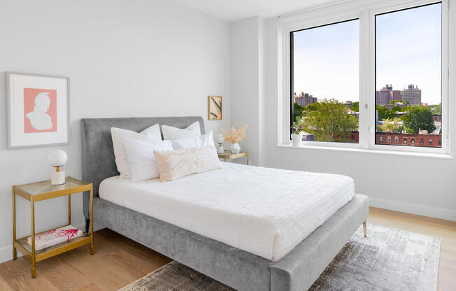  Apartment bedroom with wood floors, modern furniture, and a treetop view of Prospect Heights