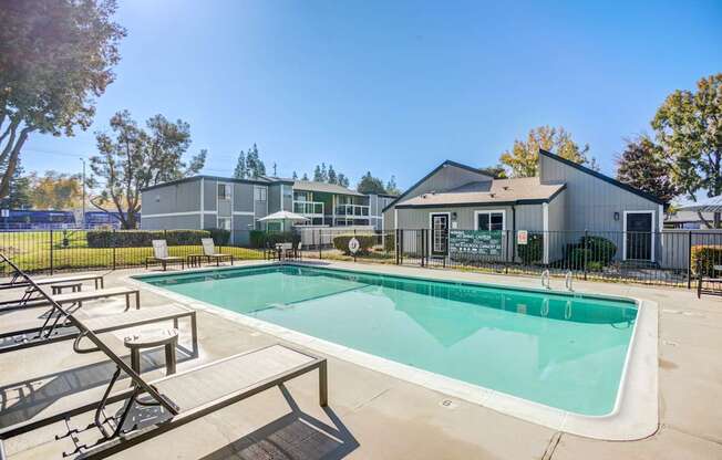 A swimming pool with a bench and a building in the background.