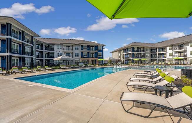 a swimming pool with lounge chairs in front of apartment buildings