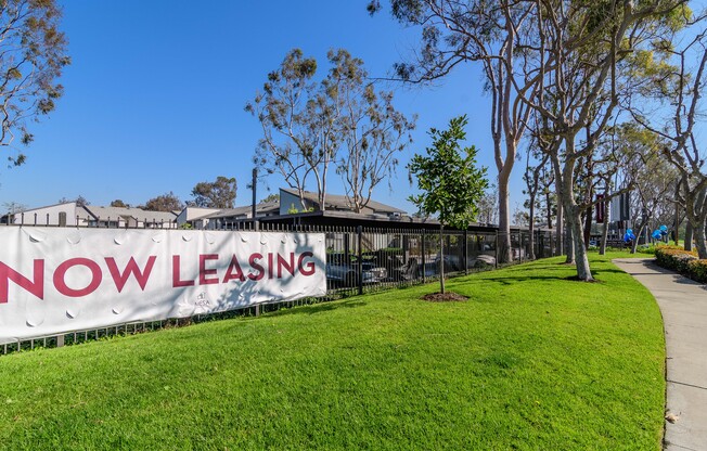 A leasing sign is displayed on a fence in front of a building.