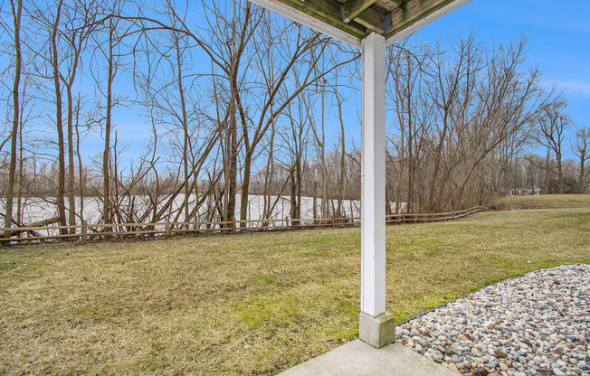 a private patio with a view of a pond and trees at Canal 2 Apartments, Lansing, Michigan