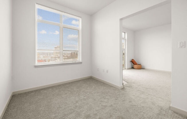 A room with a large window and a carpeted floor.