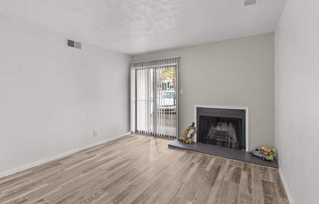 A living room with a fireplace and a window with curtains.