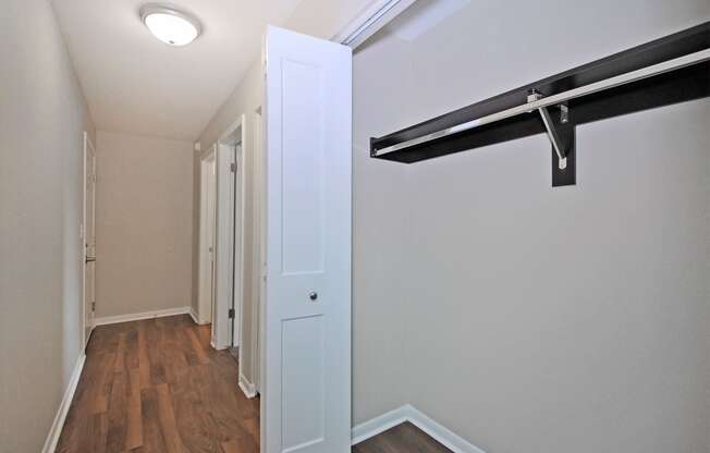 a bedroom with a closet and a white door and a hallway with wood floors