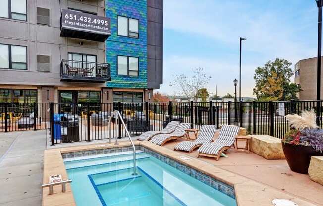 a swimming pool with lounge chairs next to a building