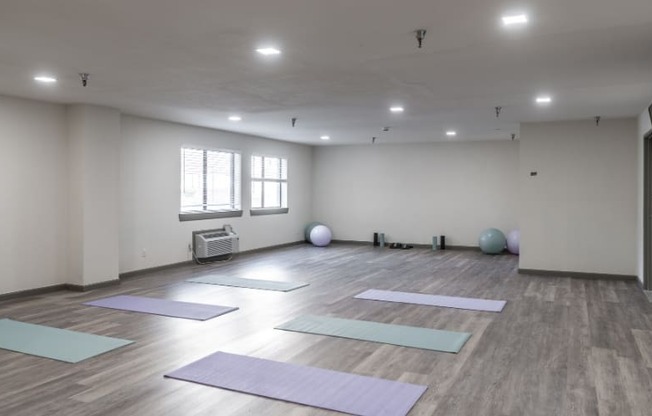 a large room with yoga mats on the floor and a window