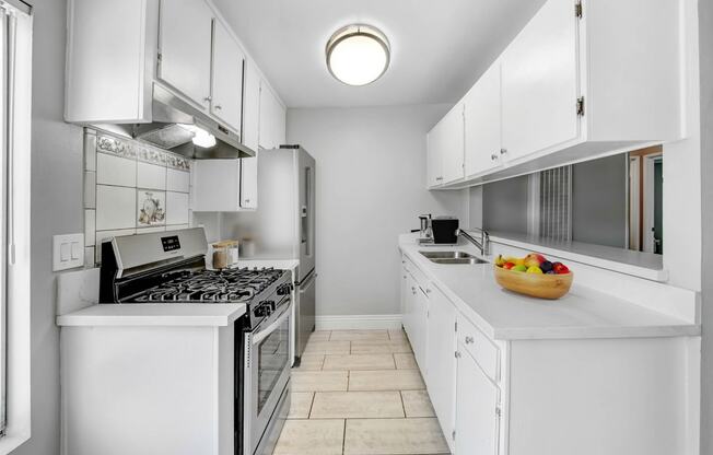 a white kitchen with a bowl of fruit on the counter