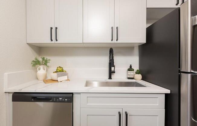 a white kitchen with white cabinets and a black dishwasher