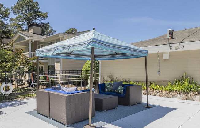 A patio with a blue canopy and a white fence.